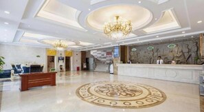 A hotel lobby with a reception desk, a chandelier, a patterned floor, and a staircase. - Vienna Hotel Huizhou (Huizhou)