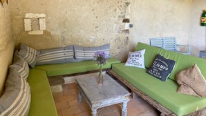 A rustic room with a green sofa, striped pillows, a small table, and a vase with flowers. - Pretty Farmhouse / Private pool / 4 Doubles with en-suites & 1 Twin  / Sleeps 10 (Saint-Séverin)