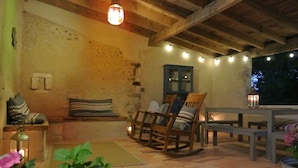 A rustic outdoor seating area with wooden furniture, string lights, and a stone wall. - Pretty Farmhouse / Private pool / 4 Doubles with en-suites & 1 Twin  / Sleeps 10 (Saint-Séverin)