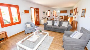 Amplia sala de estar con un sofá gris, una mesa de centro y un comedor al fondo.