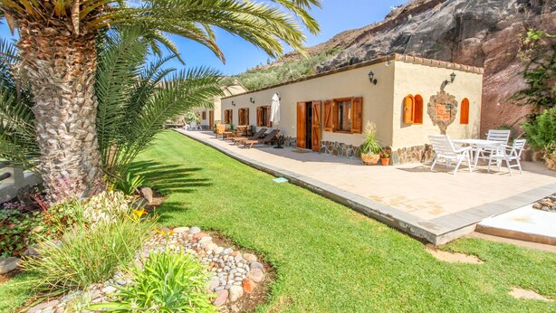 Un edificio con patio, mobiliario exterior y una palmera.
