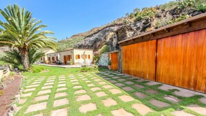 Un patio con una palmera, un sendero de piedra y un edificio de madera con garaje.