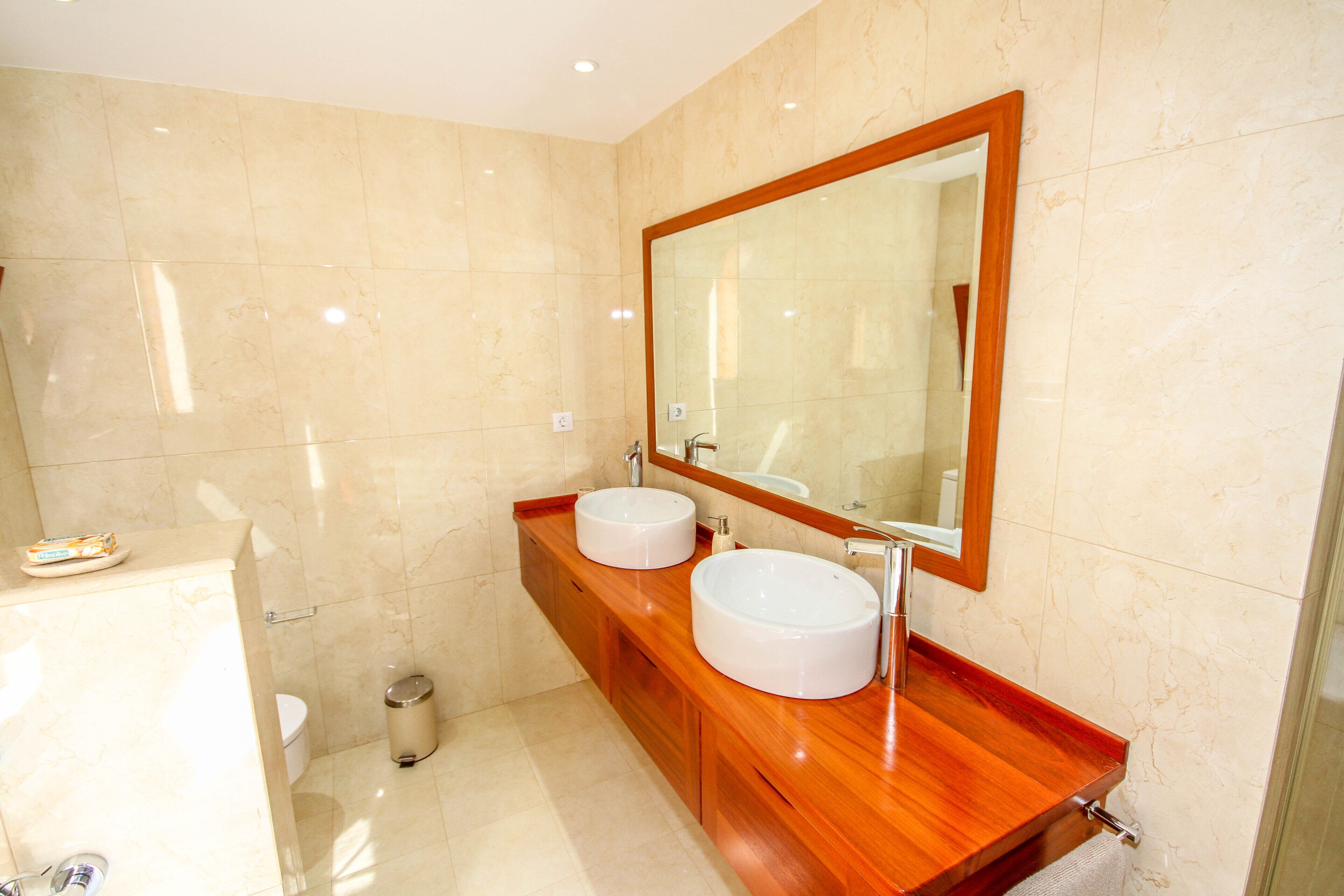 Une salle de bain moderne avec deux lavabos, un grand miroir et des toilettes.