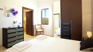 Ein Schlafzimmer mit Bett, Kommode, Sessel und Kleiderschrank.