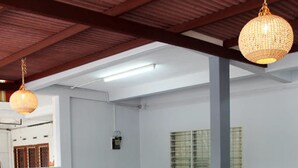 A spacious room with a high ceiling, a dining table with benches, a hanging light fixture, and a window with blinds. - Gen-Ji Cottage (Malacca City)
