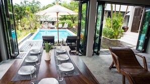A dining area with a pool view, a table set for six, and a lounge chair. - Luxury villa, private beach, infinity pool. Fully serviced. Beautiful sunsets (koh chang)