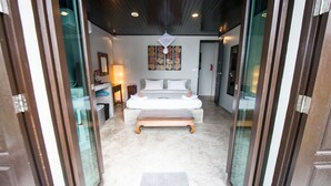 A modern bedroom with a large bed, a bench, a small table, and a wall-mounted artwork. - Luxury villa, private beach, infinity pool. Fully serviced. Beautiful sunsets (koh chang)