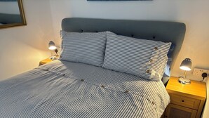 A neatly made bed with striped bedding, two bedside lamps, and a wooden nightstand with a drawer. - The Old Shippon, Crackington Haven, Bude, Cornwall, walk to the Beach Pub. (Crackington Haven)