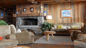 A cozy living room with a stone fireplace, wooden walls, and a comfortable seating area. - luxury apartment at the foot of the slopes, indoor pool.  (Les Belleville)