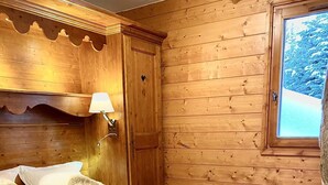 A wooden cabin bedroom with a bed, pillows, and towels. - luxury apartment at the foot of the slopes, indoor pool.  (Les Belleville)
