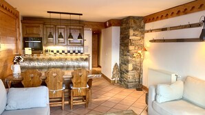 A cozy living room with a sofa, a coffee table, and a dining area with a wooden table and chairs. - luxury apartment at the foot of the slopes, indoor pool.  (Les Belleville)