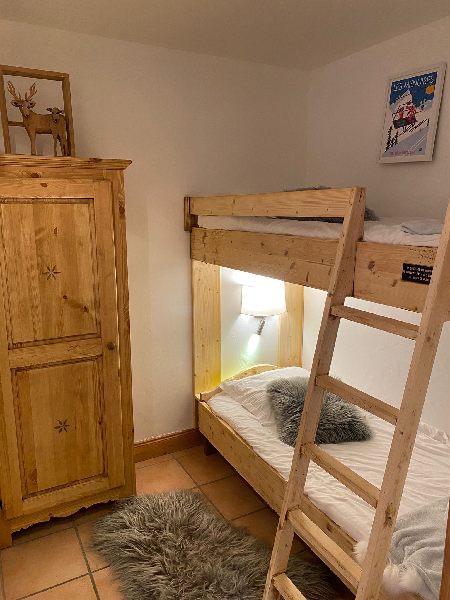 Habitación con literas, un armario de madera, una alfombra mullida y un cartel en la pared.
