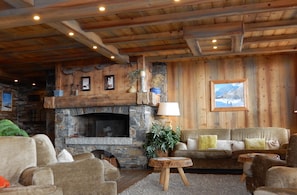 A cozy living room with a stone fireplace, wooden walls, and a comfortable seating area. - luxury apartment at the foot of the slopes, indoor pool.  (Les Belleville)
