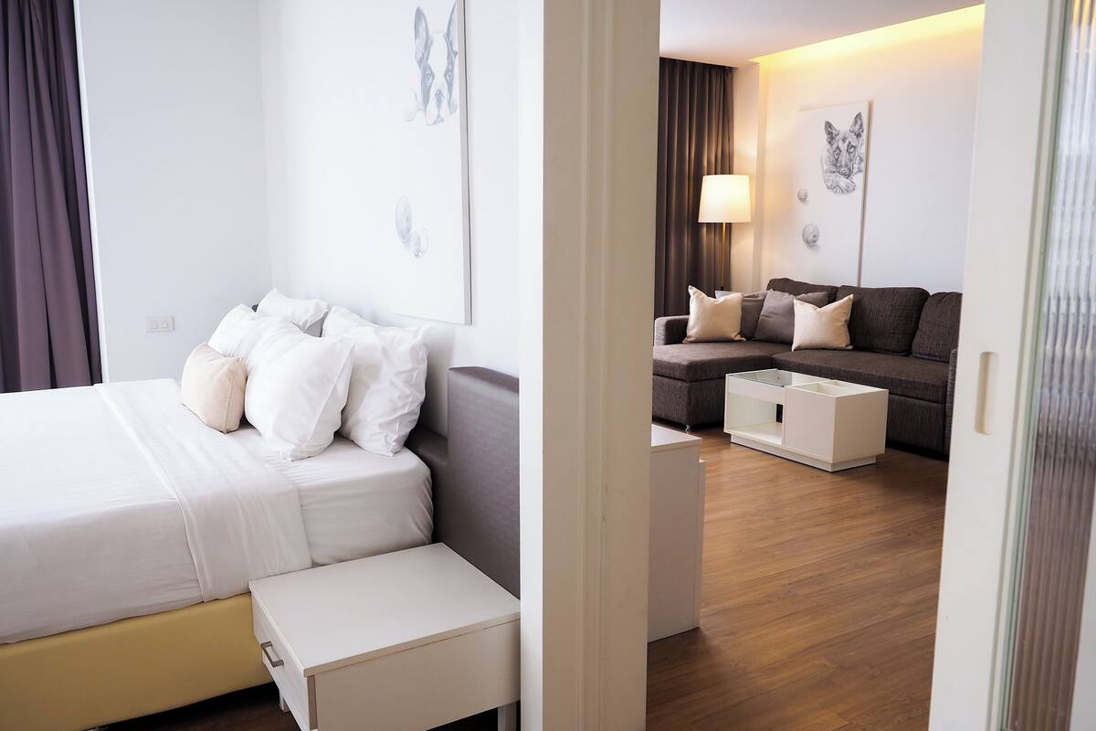 A modern hotel room with a bed, a sofa, a small table, and a cabinet.