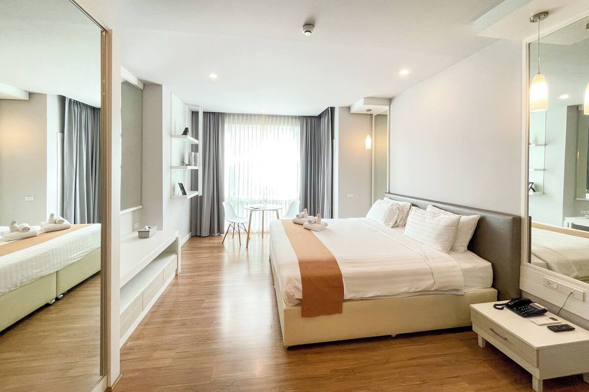 A modern hotel room with a large bed, bedside tables, a desk, and a chair.