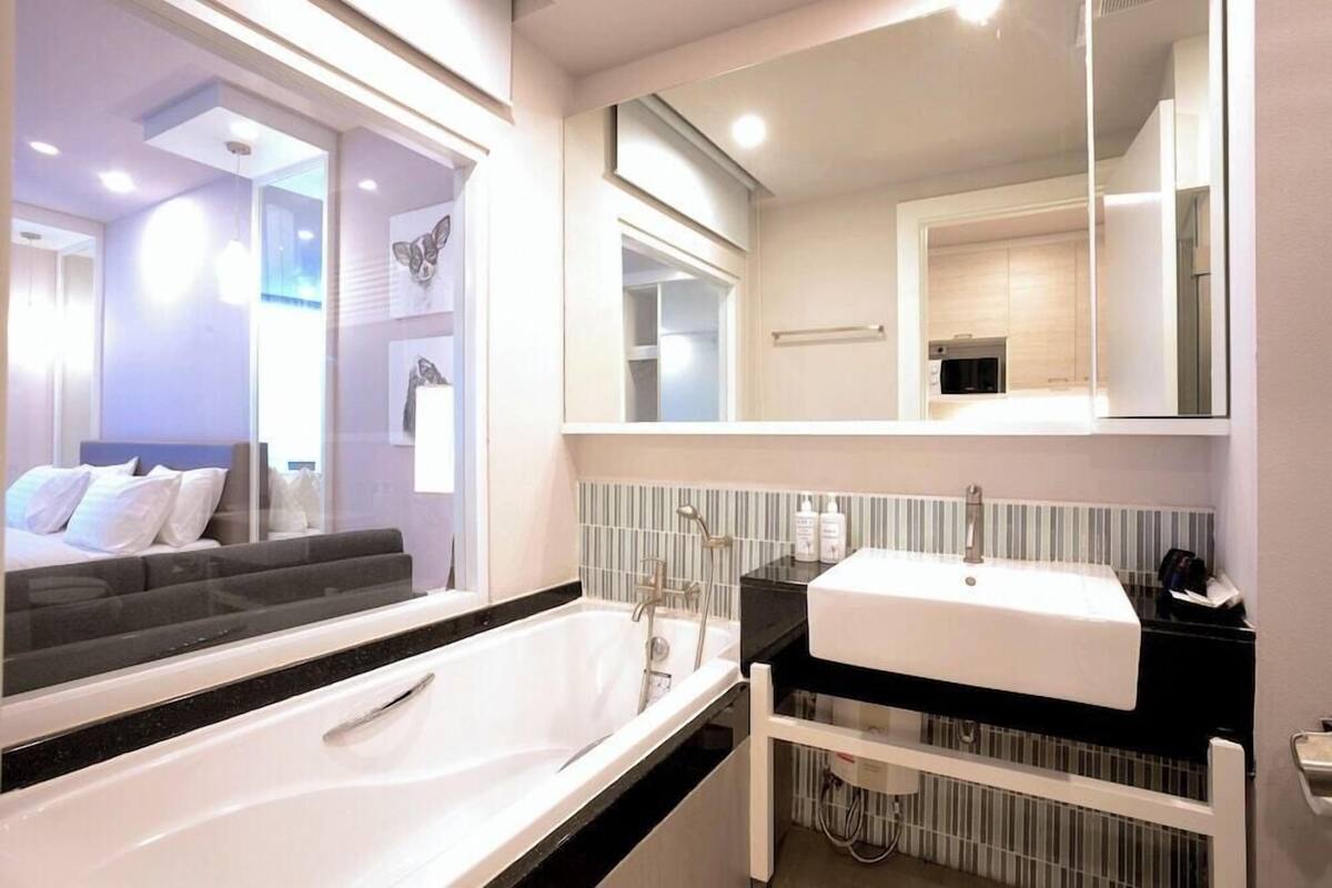 A modern bathroom with a large bathtub, a white sink, and a mirror above the sink.