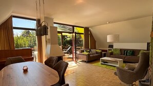 Ein modernes Wohnzimmer mit einem Holzesstisch, Ledersofas und einem großen Schiebeglasfenster zum Patio.