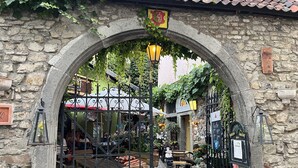 Ein Bogen führt zu einem Innenhof mit Steinmauern, einer hölzernen Bank und einem Schild, das ein Restaurant anzeigt.