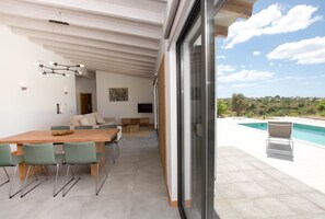 A modern dining area with a wooden table and green chairs, a sofa, and a TV. - Casa da Vinha - Carvoeiro - Pool villa for 6 persons with sea view on pur nature (Carvoeiro)