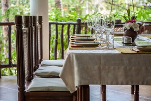 A dining table set with plates, glasses, and cutlery, with a view of greenery in the background. - Large luxury beachside villa with a pool, guesthouse, cook, gardener, and maid (Diani Beach)
