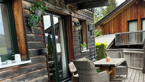 A wooden deck with outdoor furniture, a sliding glass door, and a small table with a drink. - Cabin with great location and view of the Bischofsmütze Mountain (Annaberg im Lammertal)