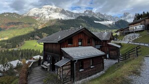 A wooden cabin with a porch, set against a backdrop of snow-capped mountains and a forested valley. - Cabin with great location and view of the Bischofsmütze Mountain (Annaberg im Lammertal)