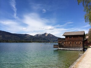 Una cabaña de madera junto a un lago, con montañas al fondo.