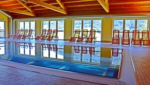 An indoor swimming pool with multiple lounge chairs and large windows offering views of a snowy landscape. - Cabin with great location and view of the Bischofsmütze Mountain (Annaberg im Lammertal)