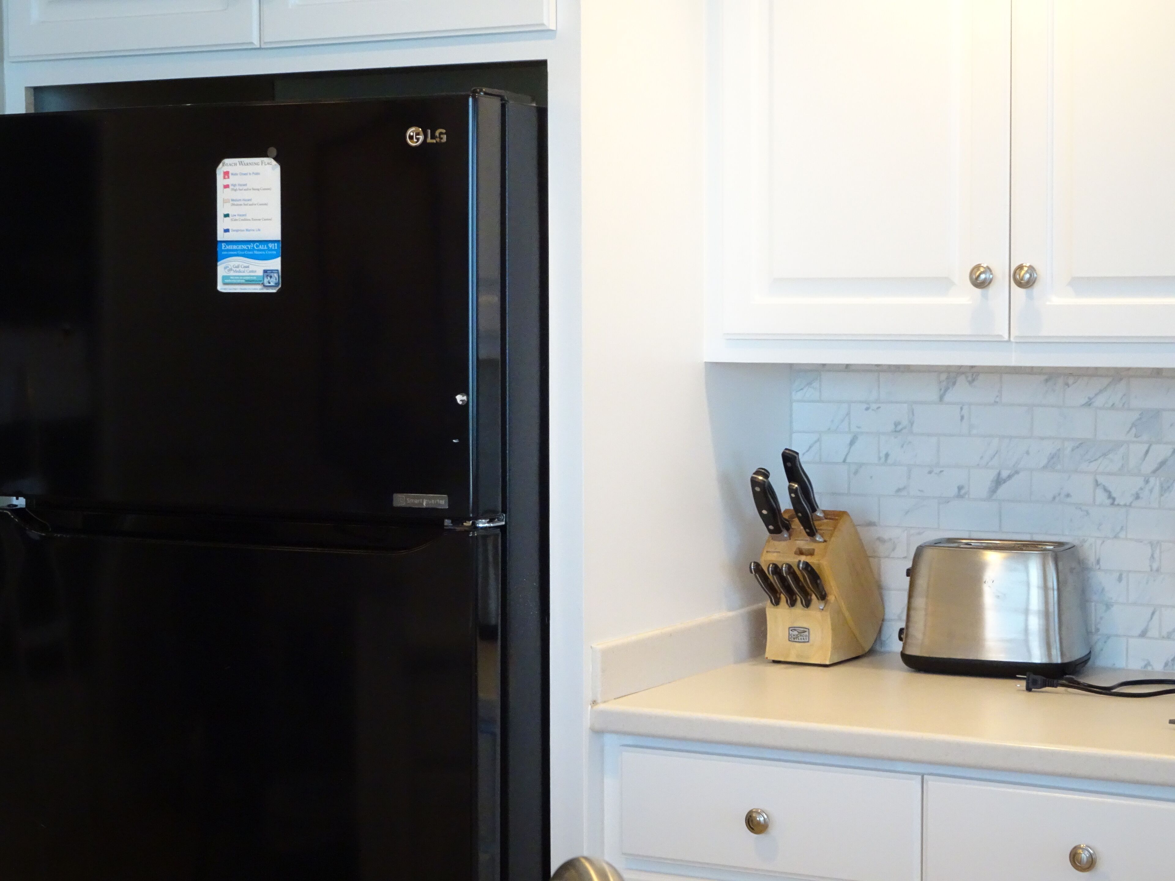 A kitchen with a black LG refrigerator, a knife block, and a toaster on the counter.