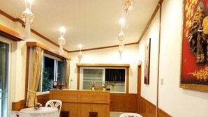 A dining area with two round tables, white chairs, a wooden counter, and pendant lighting. - Na Soi 5 Chiangkhan (Chiang Khan)