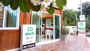 A building with a wooden facade, glass doors, and a signboard with contact information. - Na Soi 5 Chiangkhan (Chiang Khan)