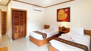 A hotel room with two beds, a wooden door, an air conditioning unit, and a decorative wall piece. - Na Soi 5 Chiangkhan (Chiang Khan)