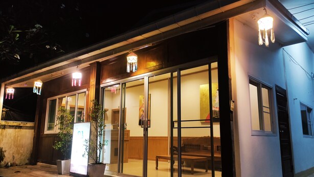 A modern building with large glass doors, a bench outside, and potted plants. - Na Soi 5 Chiangkhan (Chiang Khan)