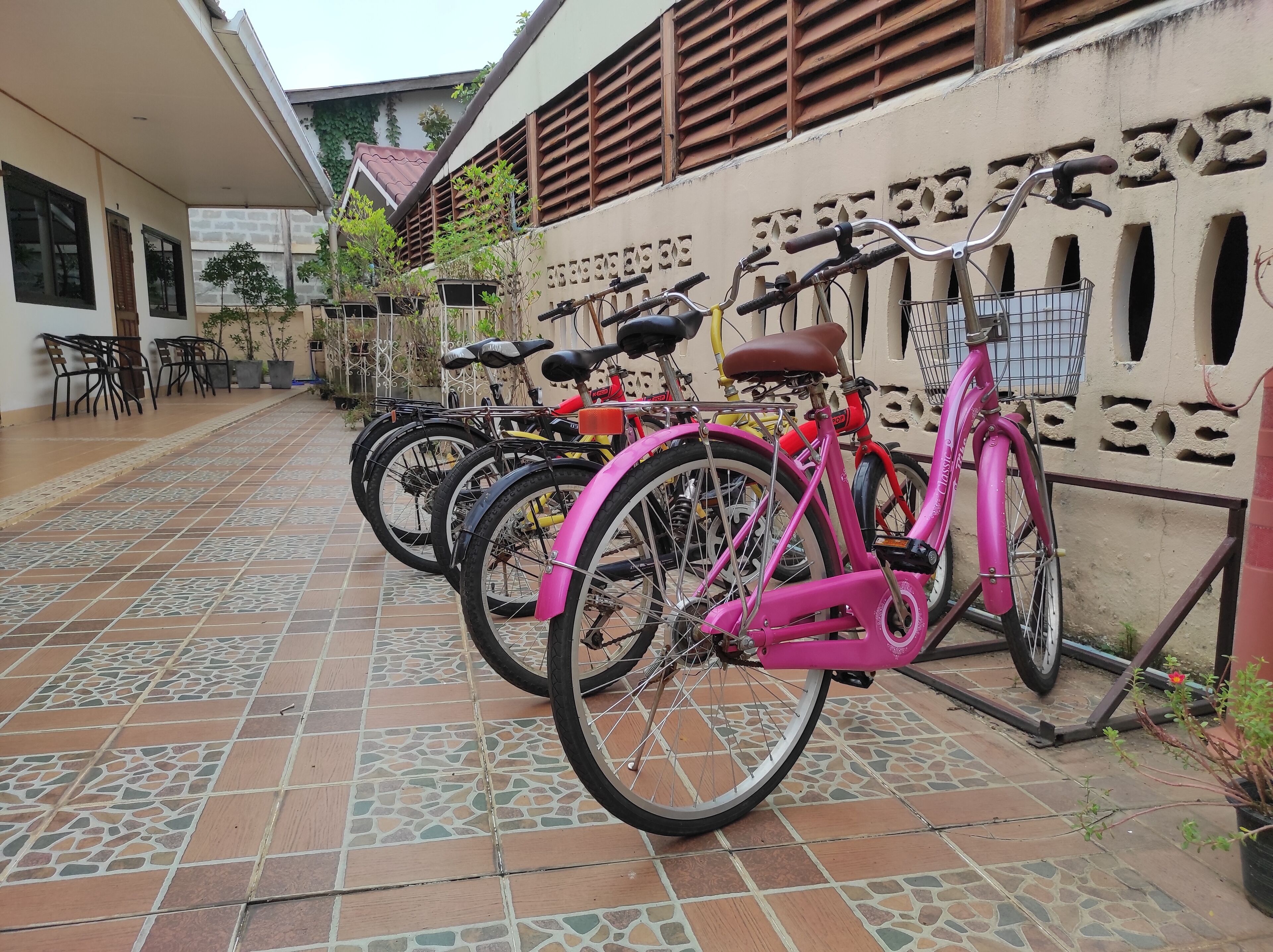 A courtyard with tiled flooring, a row of bicycles, and a building with a decorative wall.