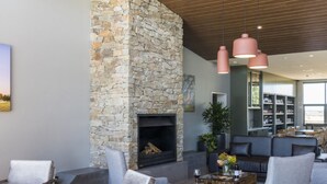A modern living room with a stone fireplace, comfortable seating, and a bookshelf.