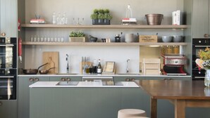 A modern kitchen with a central island, built-in appliances, and open shelving with various kitchen items.