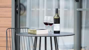 Una mesa redonda con una botella de vino, copas, un libro y una caja pequeña.