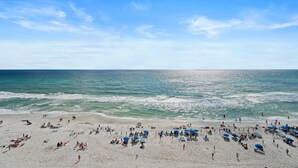 En strand med många parasoller och solstolar, vilket tyder på att det är ett område med hotell och andra faciliteter för strandgäster.