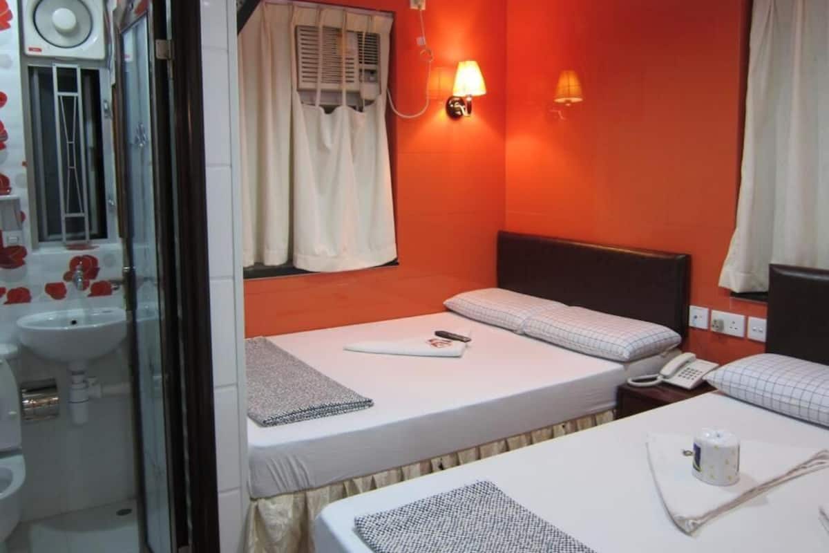 A compact hotel room with a single bed, bedside table, and a small desk with a lamp.