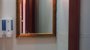 A bathroom with a white sink, a gold-framed mirror, and a wall-mounted soap dispenser. - Premium Lounge (Kowloon)