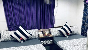 A modern living room with a sofa set, a small table with a phone and a candle, and a purple curtain. - Premium Lounge (Kowloon)