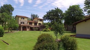 Une maison à deux étages avec une façade en pierre, un toit en tuiles et une pelouse bien entretenue.