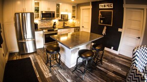 Una cocina moderna con electrodomésticos de acero inoxidable, una isla central con taburetes y un sofá con estampado blanco y negro.
