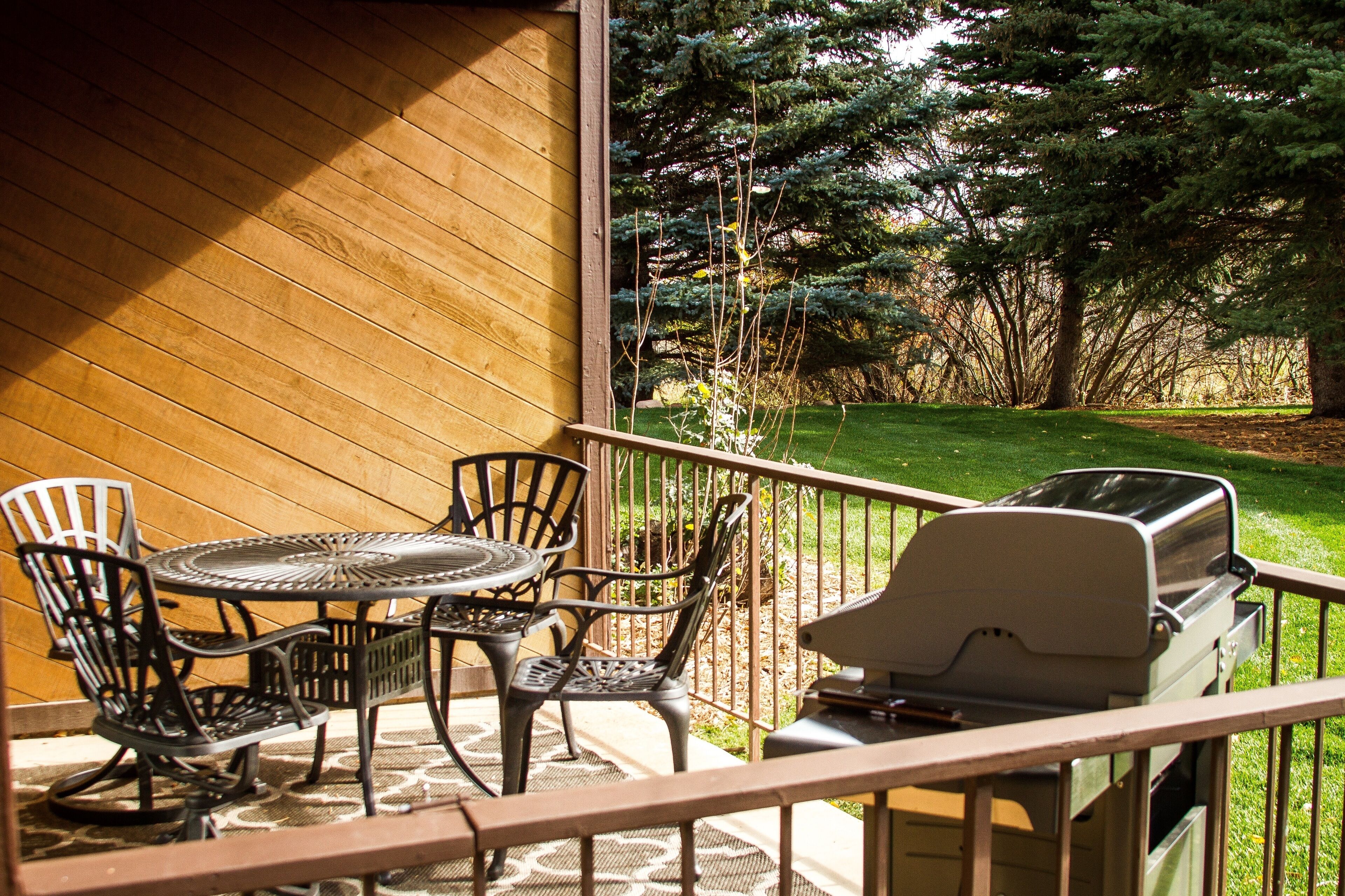 A patio with a grill, chairs, and a table.