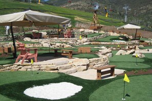 Een minigolfbaan met kunstgras, stenen muren en houten bankjes.