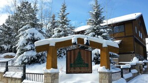 Un letrero de madera con un logotipo de un pino cubierto de nieve y el texto 'Eddie's Cabinhouse'.