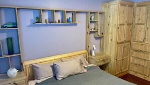 Una camera da letto con un letto, un armadio in legno, mensole con oggetti decorativi e un comodino con una lampada.
