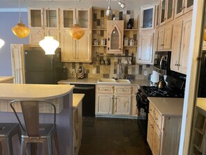 Une cuisine avec des meubles de rangement en bois, un réfrigérateur noir, une cuisinière et un évier.