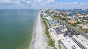 Un paysage urbain côtier avec une plage, des immeubles de grande hauteur et un port de plaisance.