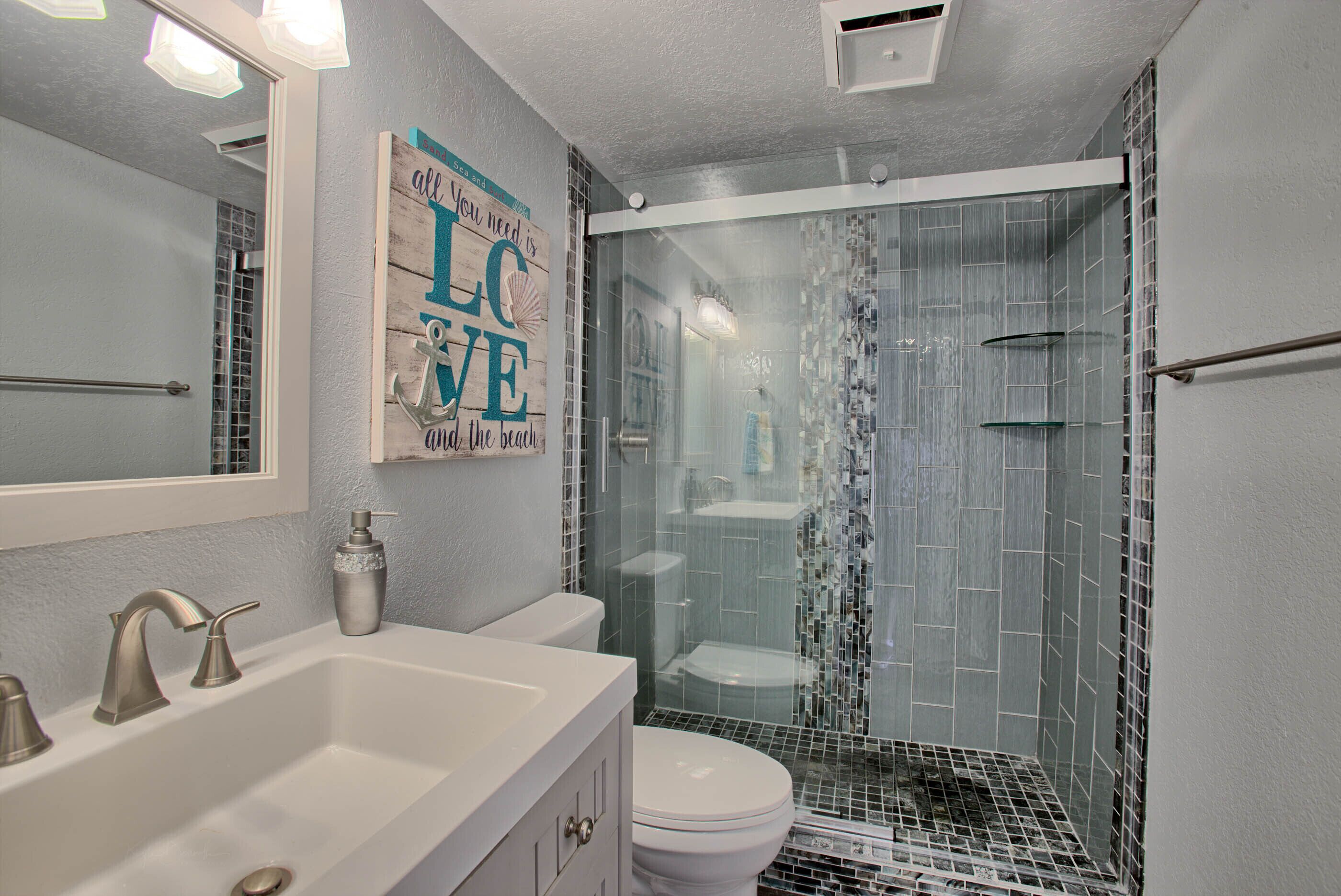 Une salle de bain avec un lavabo blanc, des toilettes et une douche aux parois en verre.